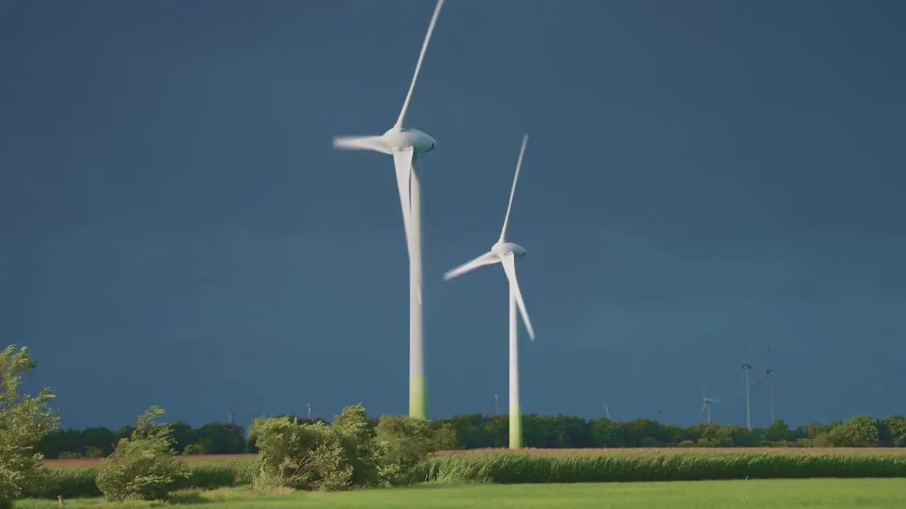 Two rotating wind turbine tower above the green landscape