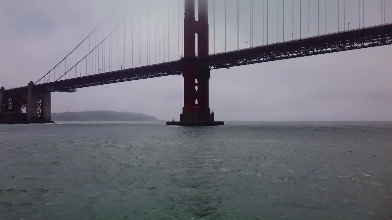 Gimbal close-up and tilting up shot from a moving boat as it approaches the underside of the Golden Gate Bridge on a foggy day