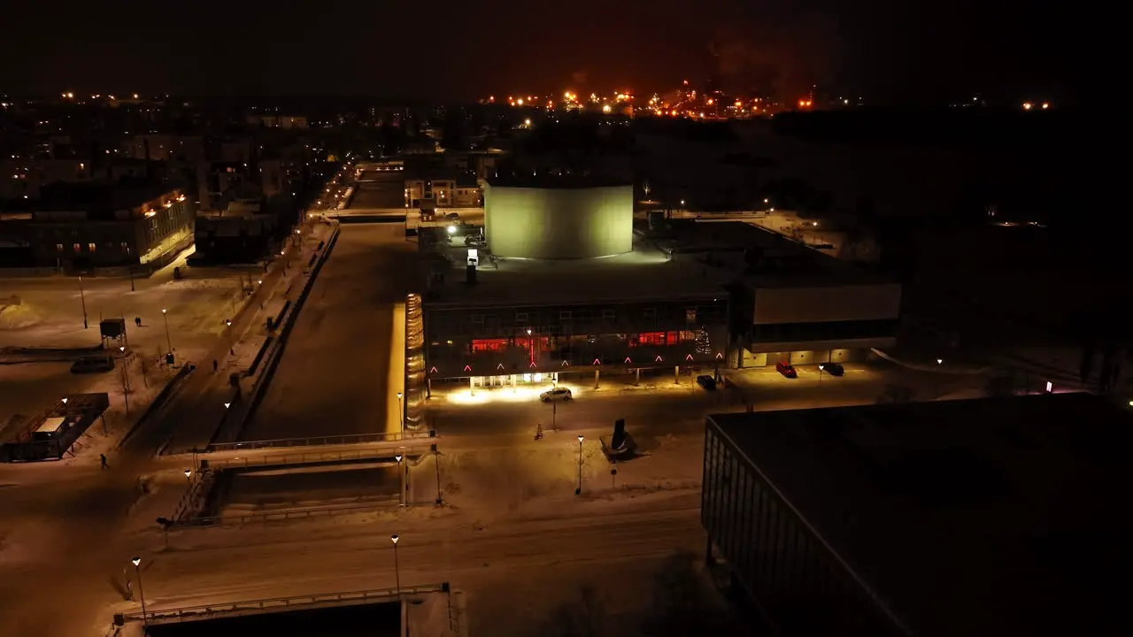 Aerial view circling the illuminated Oulu Theatre winter evening in Finland