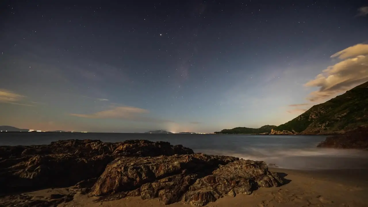 Busy Lantau island lights moving across coastline horizon under tranquil cloud forming starry night sky