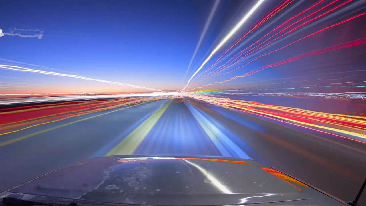 Light trail time lapse from a car at twilight reflecting off the hood of the vehicle