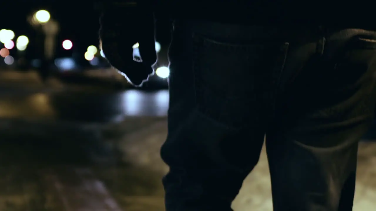 Follow shot of a hooded man walking down a cold winter street before tilting down to his feet in slow motion