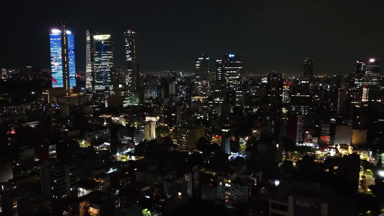 Aerial view ascending in front of the night lit skyline of Mexico city