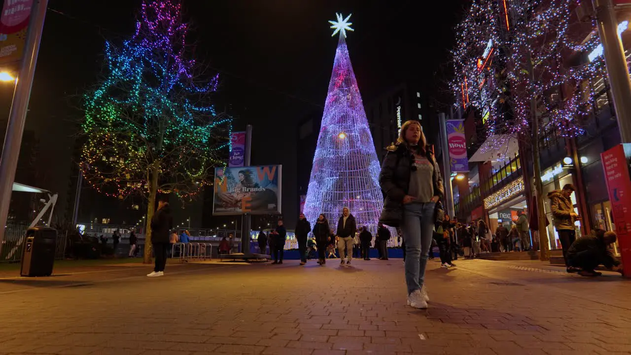 Tourists sightseeing around colourful Winterfest LED Christmas tree illuminated art installation at Wembley park at night