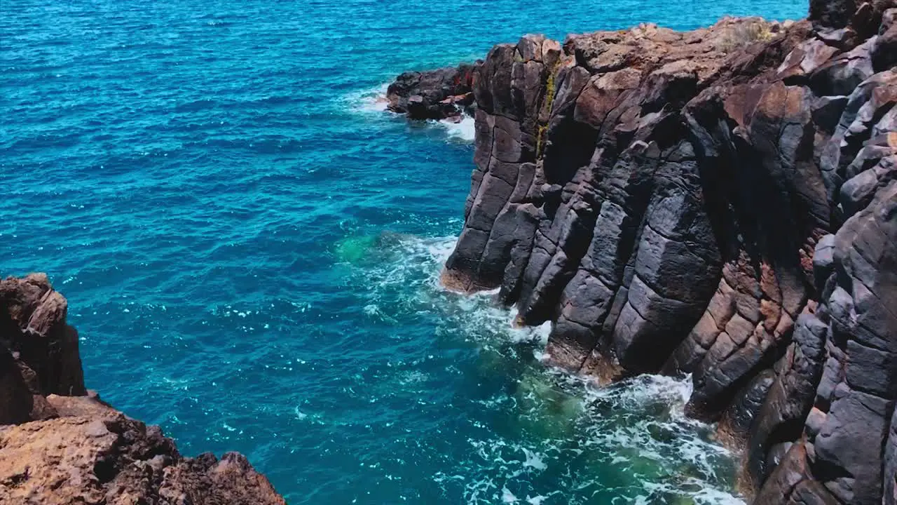 Ocean waves lap volcanic rock coastline in Madeira