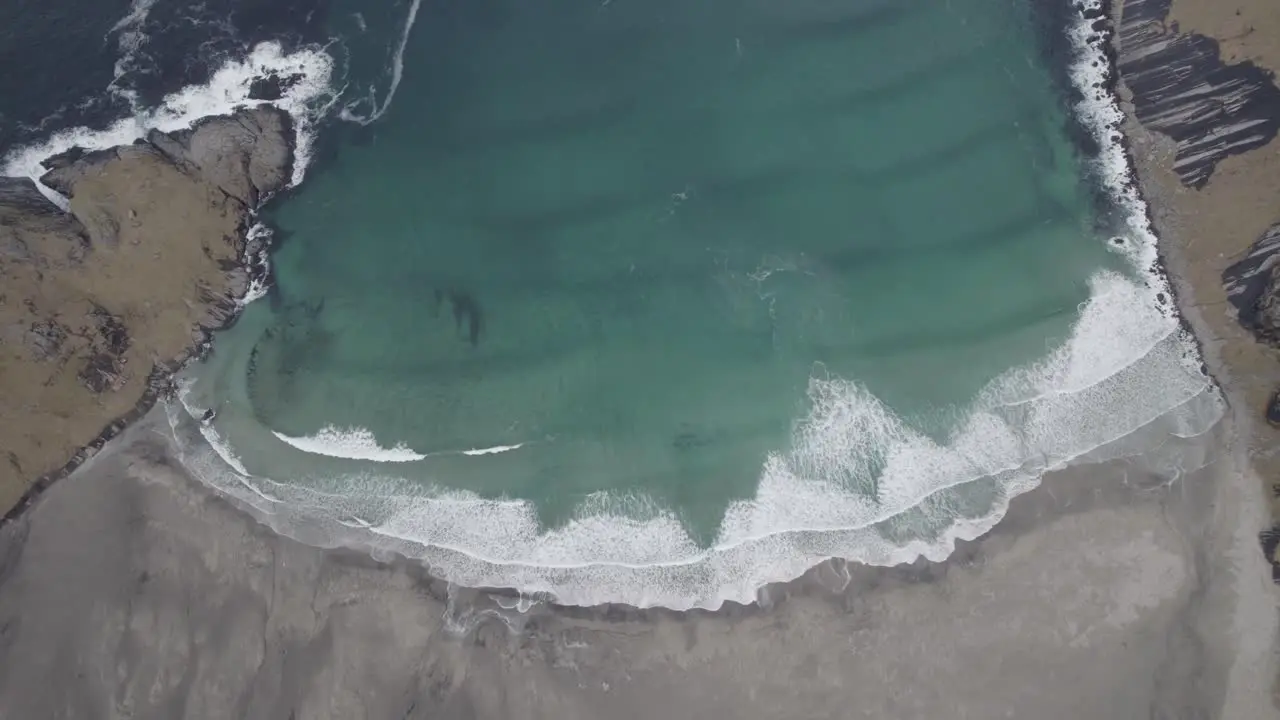 Aerial view above waves crashing a beach in Lofoten Norway birds eye drone shot