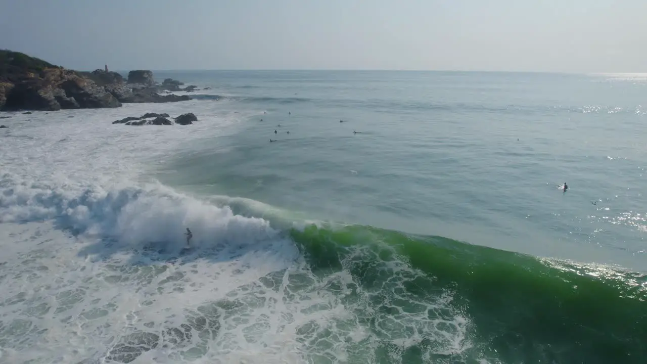 Aerial view of surfers enjoying riding Punta Zicatela shimmering sunlit blue sea waves Oaxaca Mexico