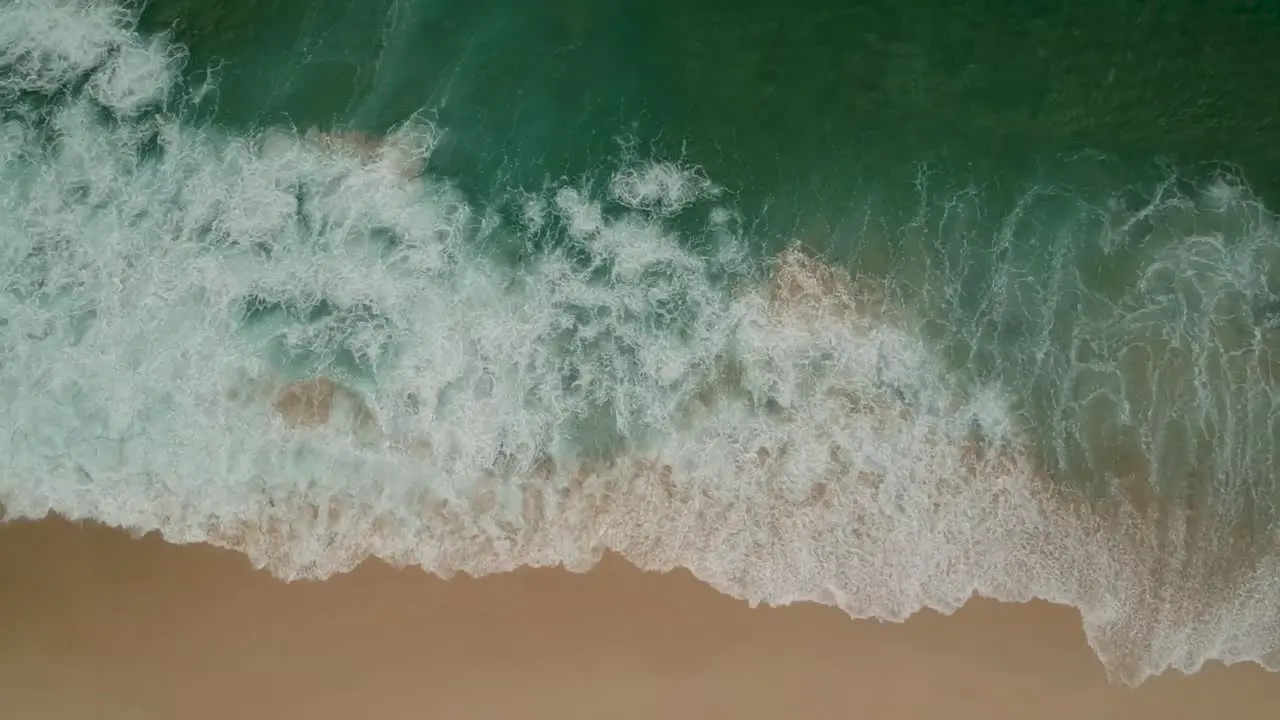 Aqua waves breaking on orange beach sand