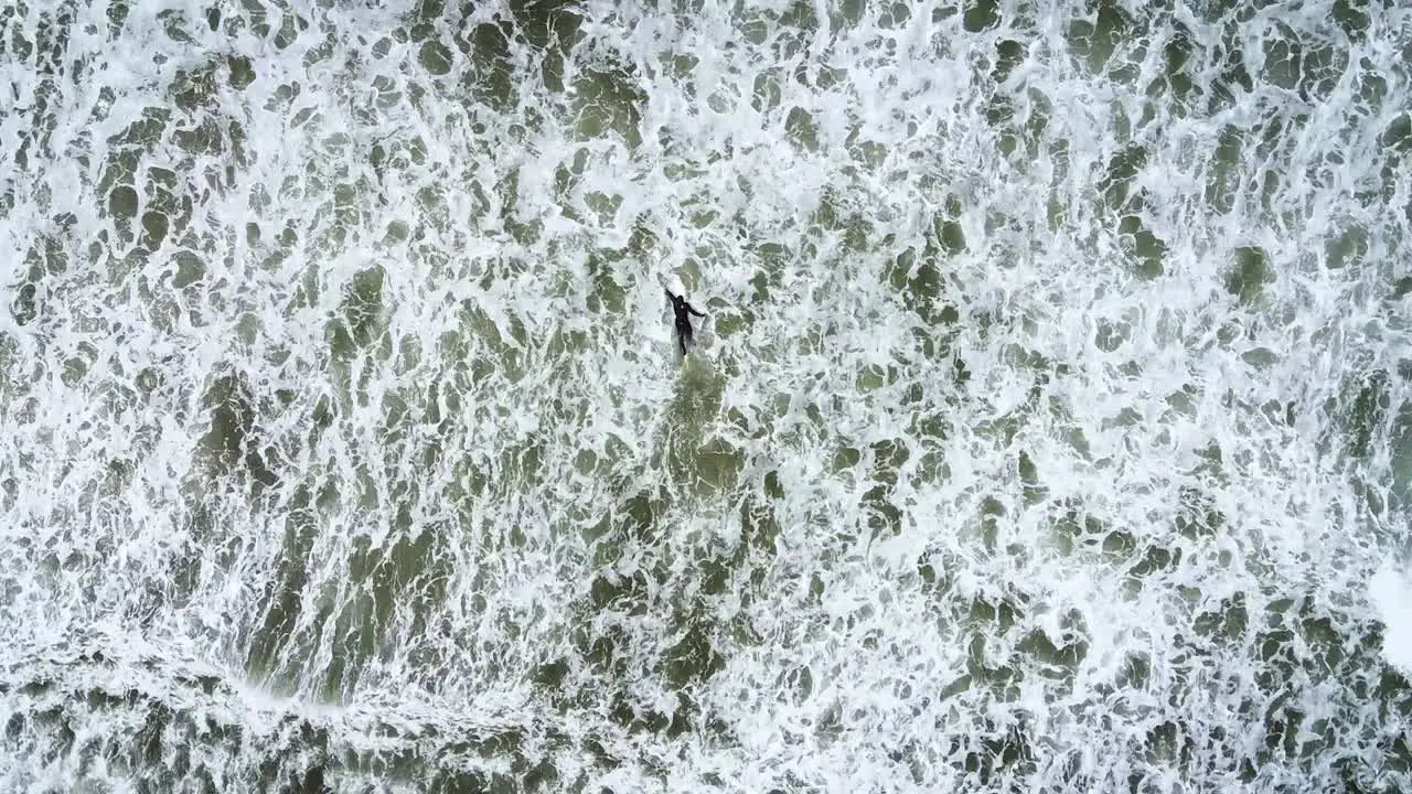 Aerial top down view of surfer treading in large waves