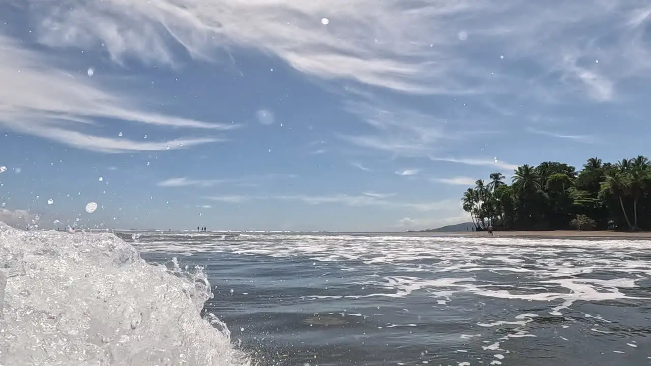 Big wave splashing over camera with view of tropical beach in Costa Rica