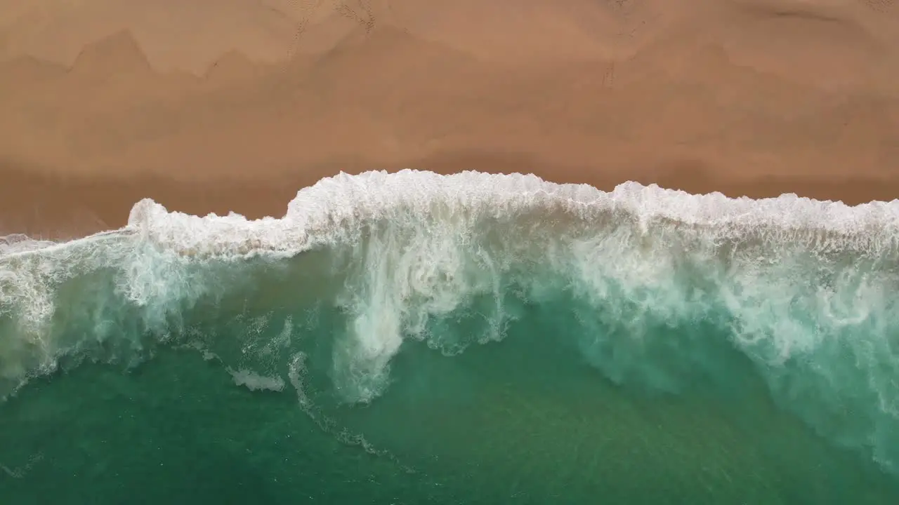 Top down view of Atlantic Ocean crashing on sandy beach in Portugal