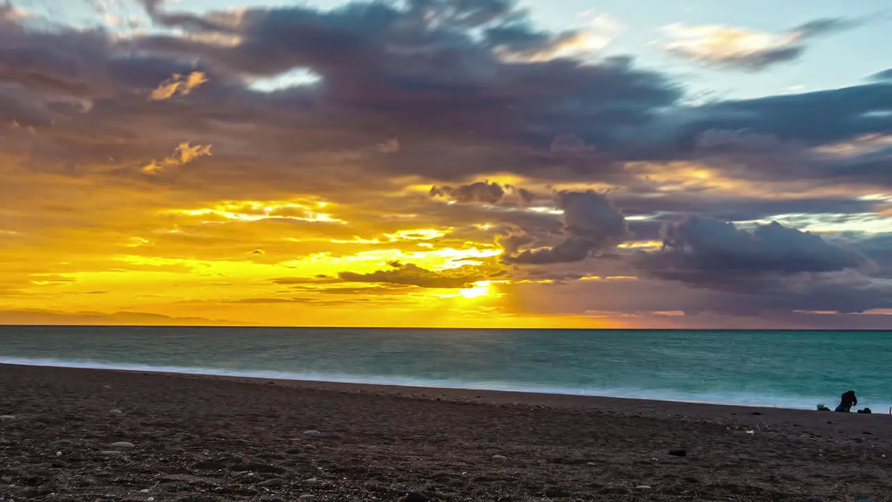 Static view of sunset over golden sky over the sea in timelapse over sandy beach