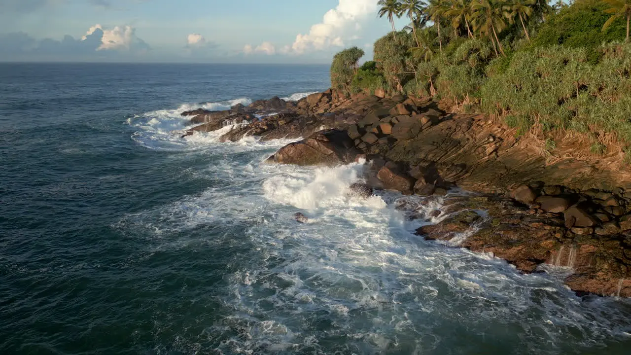 Establishing Aerial Drone Shot of Small Waves Crashing Against Rocky Coastline in Tropical Sri Lanka South Coast