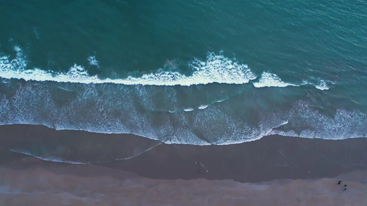 Aerial shot of foamy waves washing onto a sandy beach