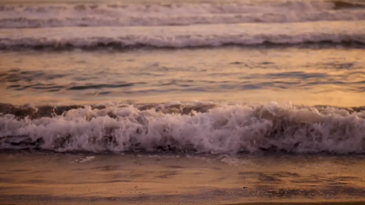 Slow motion close up of waves lapping on the shore at sunset