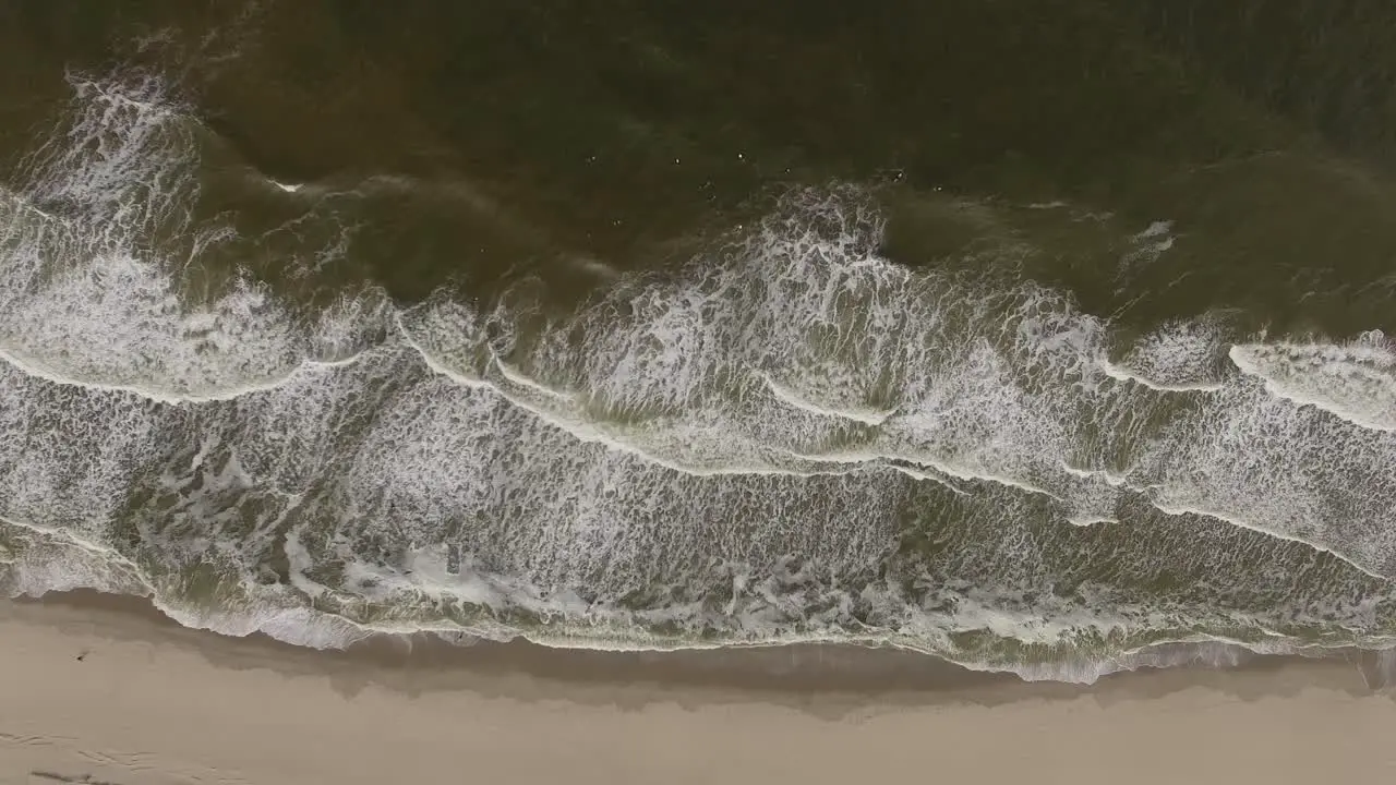 Slow motion aerial view of low tides meeting the isolated sandy beach