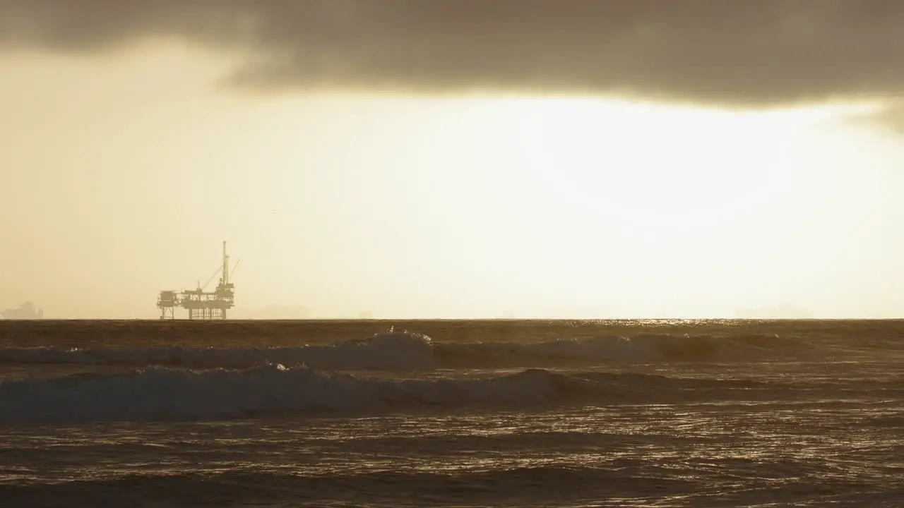 Slow Motion waves crashing with an oil rig in the background at sunset