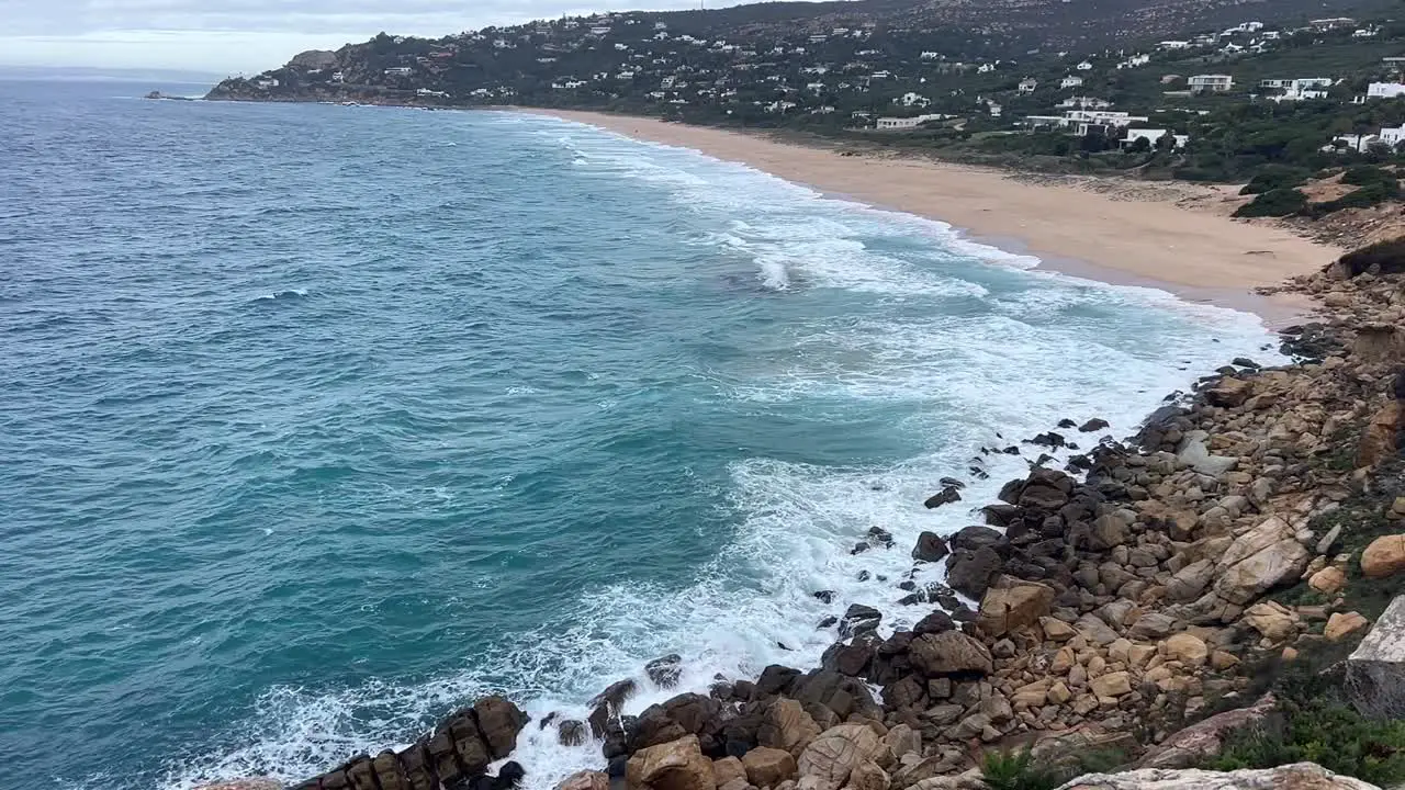 Slow motion of coastal sea waters waves are crashing at shore banks in distance visible residential area with houses