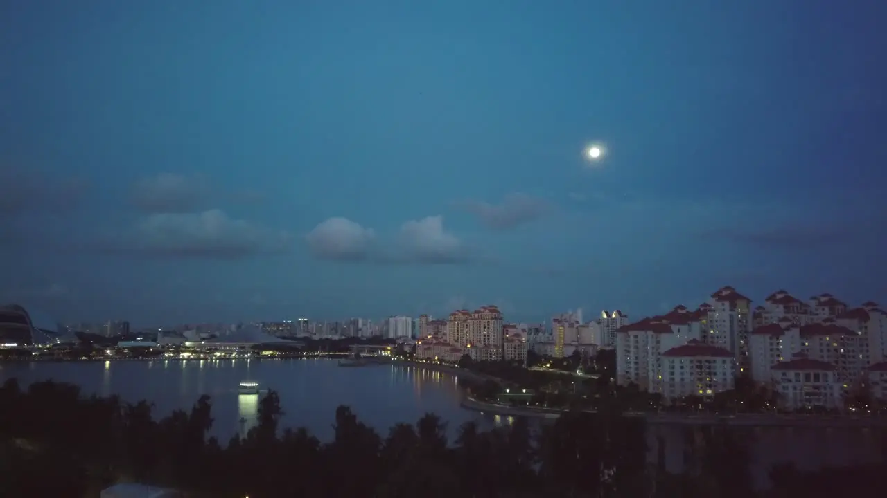 Aerial rising drone shot of condominiums in Singaproe at night with full moon