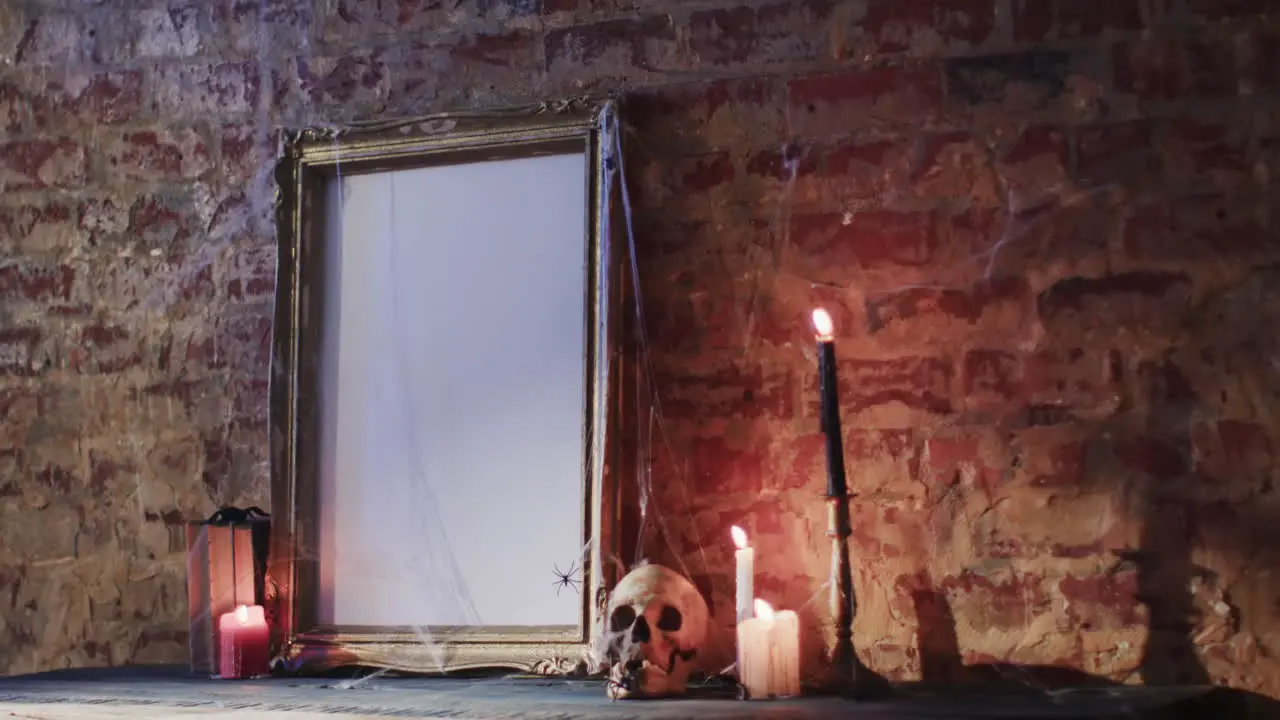 Video of stack of books frame with spider web skull and candles on brick wall background