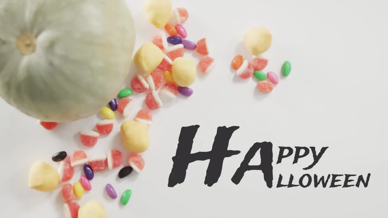 Animation of halloween text over pumpkin bucket with sweets on grey background