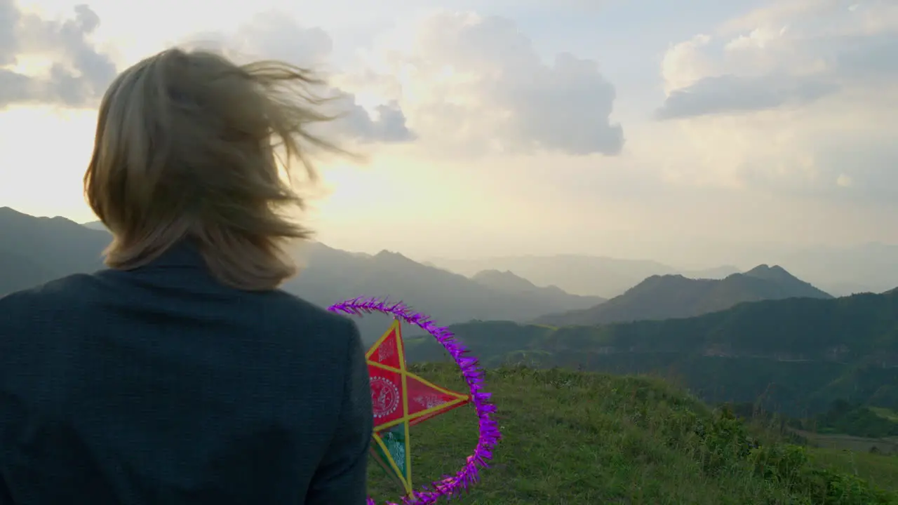 Slow motion shot of a model holding a star lantern at a mountain top at sunset