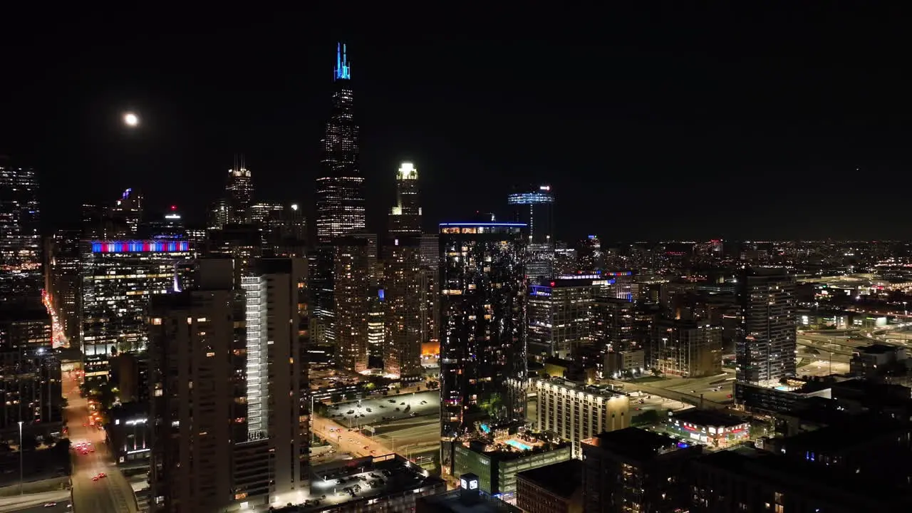 Drone shot circling the illuminated Chicago loop skyline from the west side