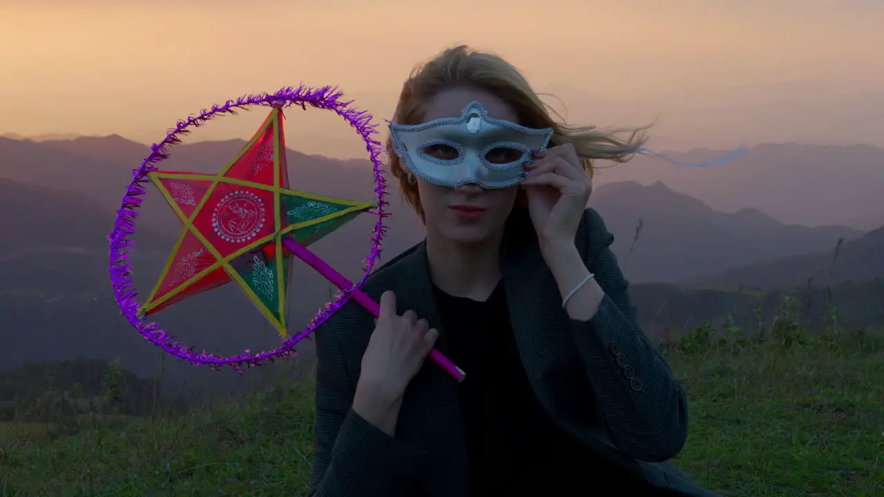 Slow motion shot of a woman wearing a mask and holding a star lantern at sunset