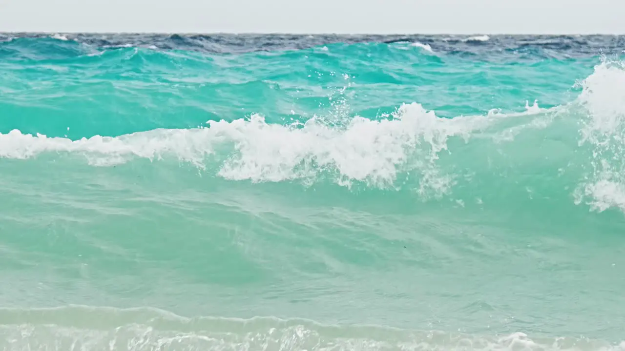 Rough stormy waves engulfing small blue buoy near coast of Caribbean island with blue turquoise sea