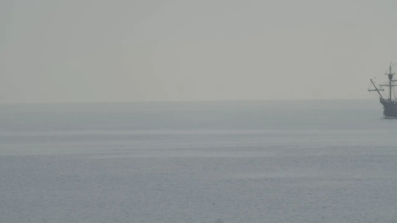 Ferdinand Magellan Nao Victoria carrack boat replica with spanish flag sails in the mediterranean at sunrise in calm sea entering the frame in slow motion 60fps