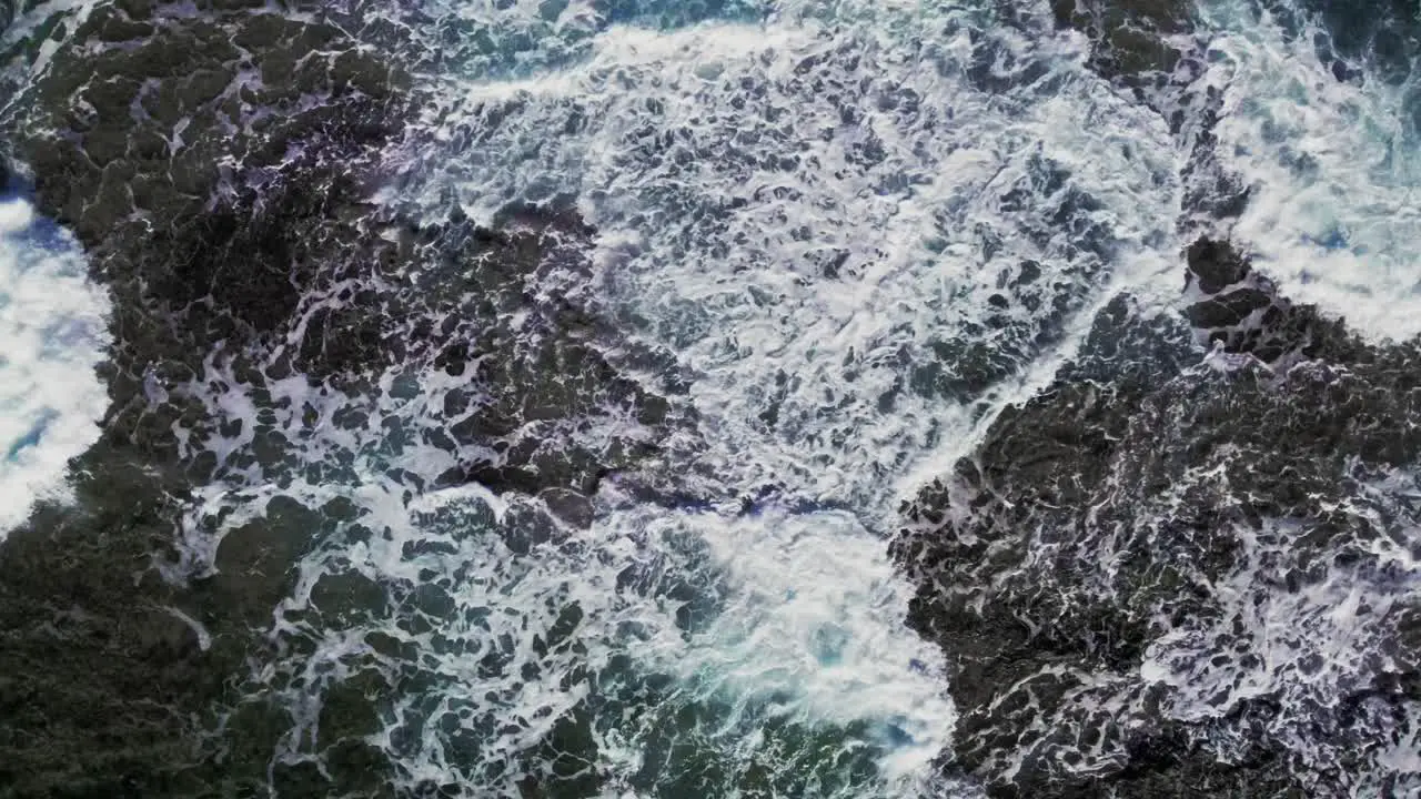 Top down aerial view large ocean waves crashing on rocks on coast