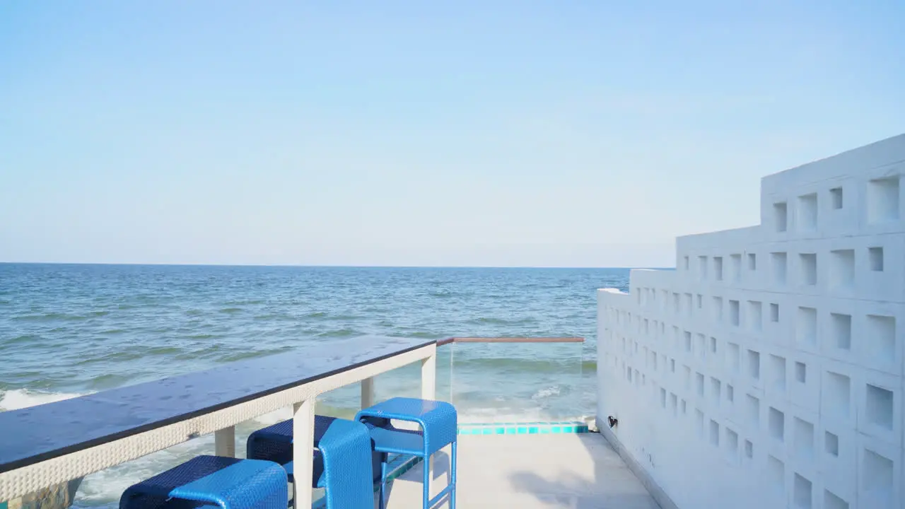 desk and bar stool near swimming pool with sea and sky background