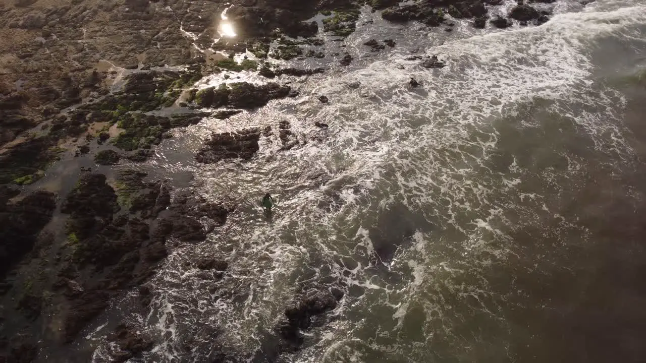 Surfer entering waters of Atlantic Ocean walking among