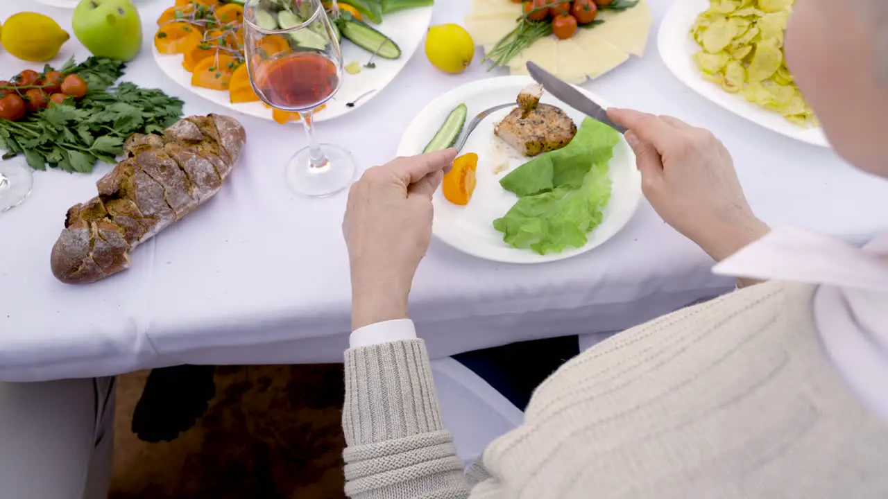 A Senior Woman Cutting Her Food With A Fork Before Eating It