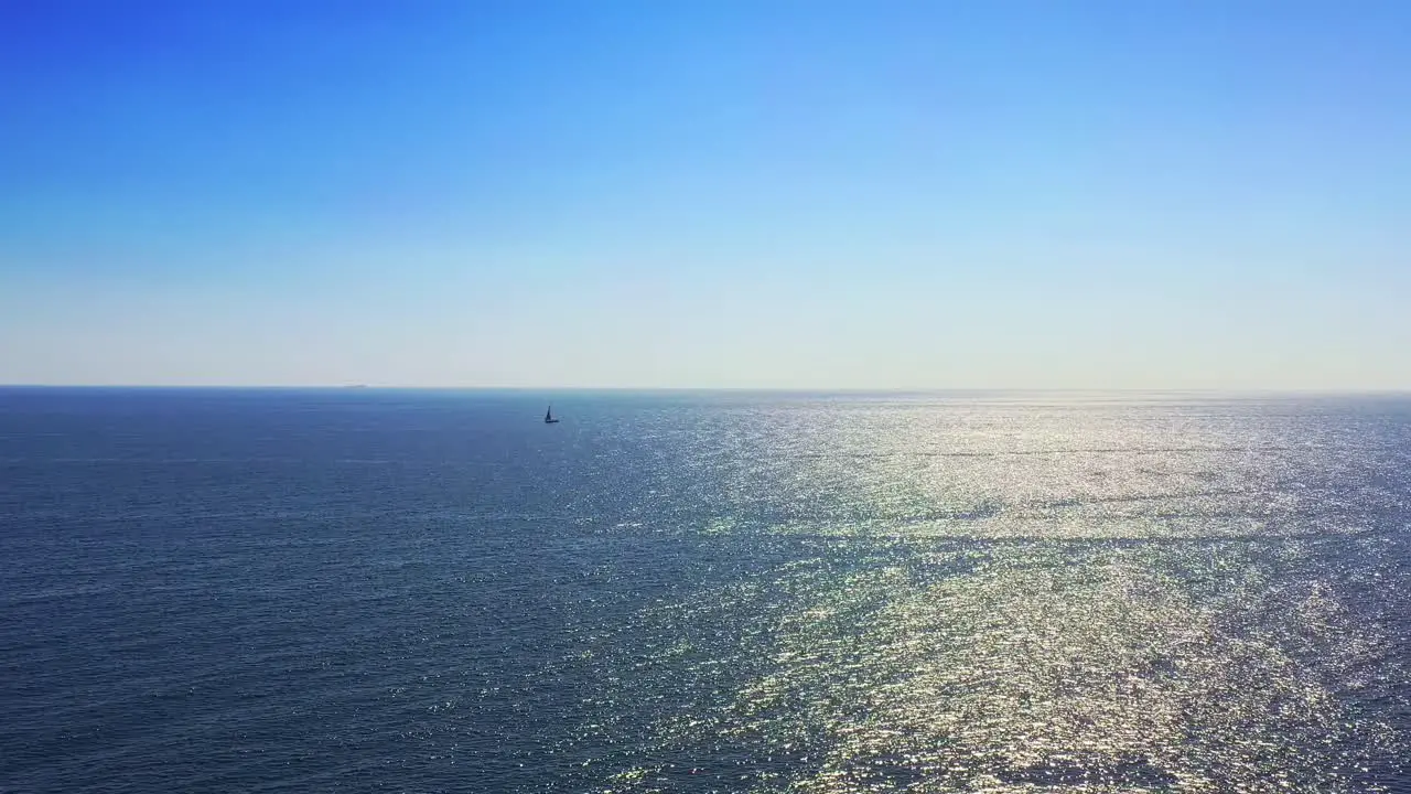 Shimmering wide view of open water and the horizon with a single boat sailing in the distance