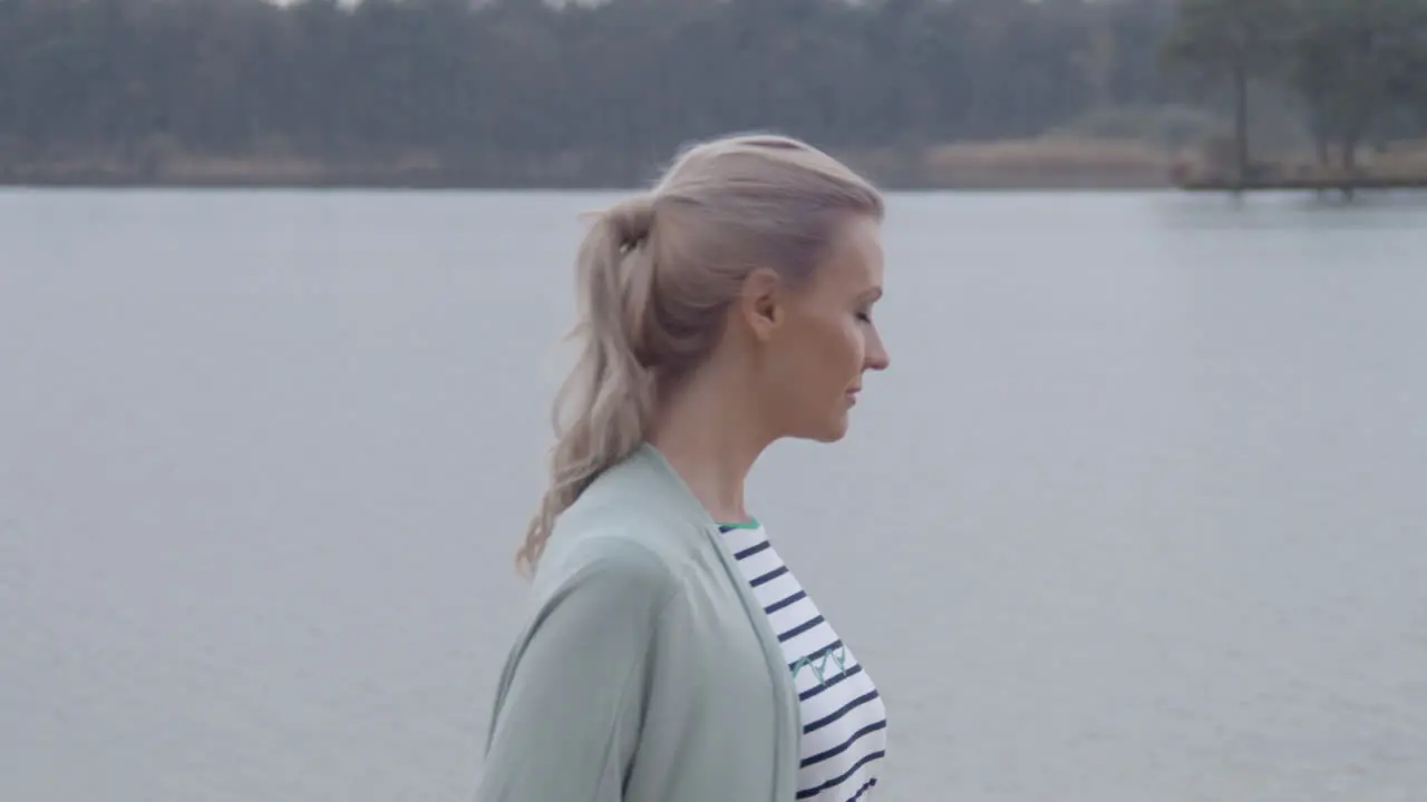 Beautiful woman standing near lakeside and turning towards camera