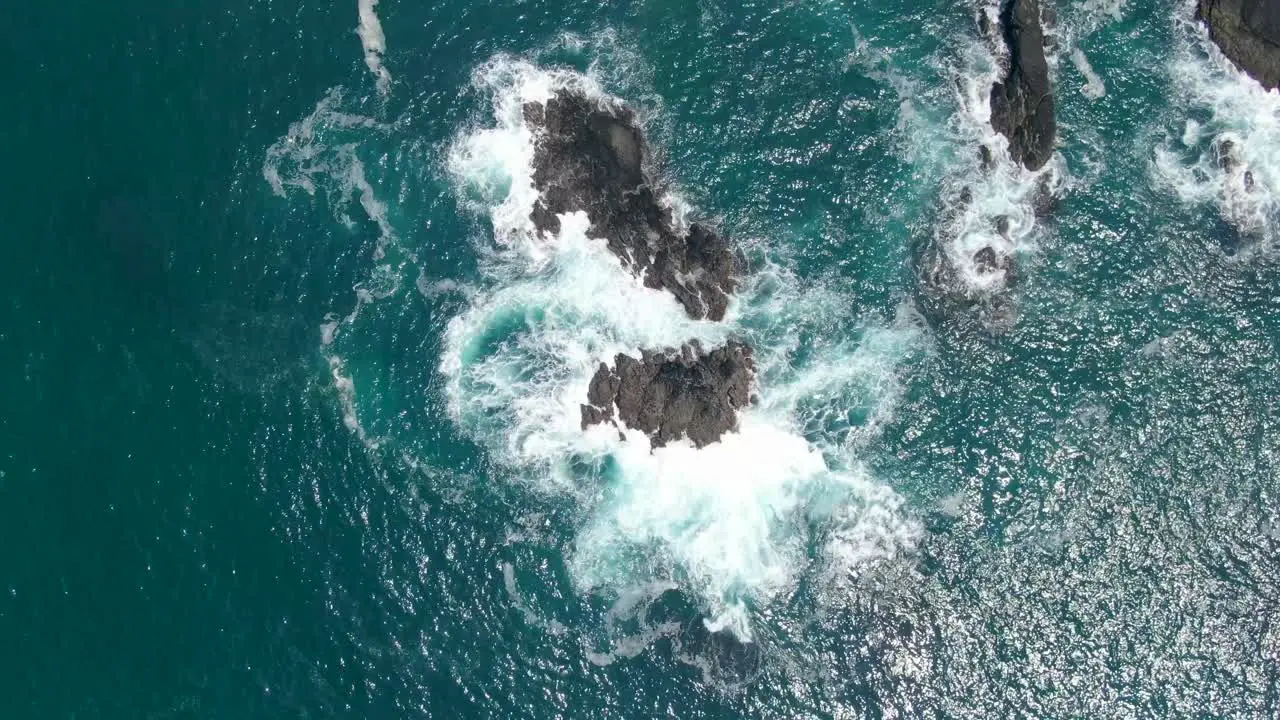 Aerial top down over sea waves crashing on rocky coast near Menganti beach Kebumen in Indonesia