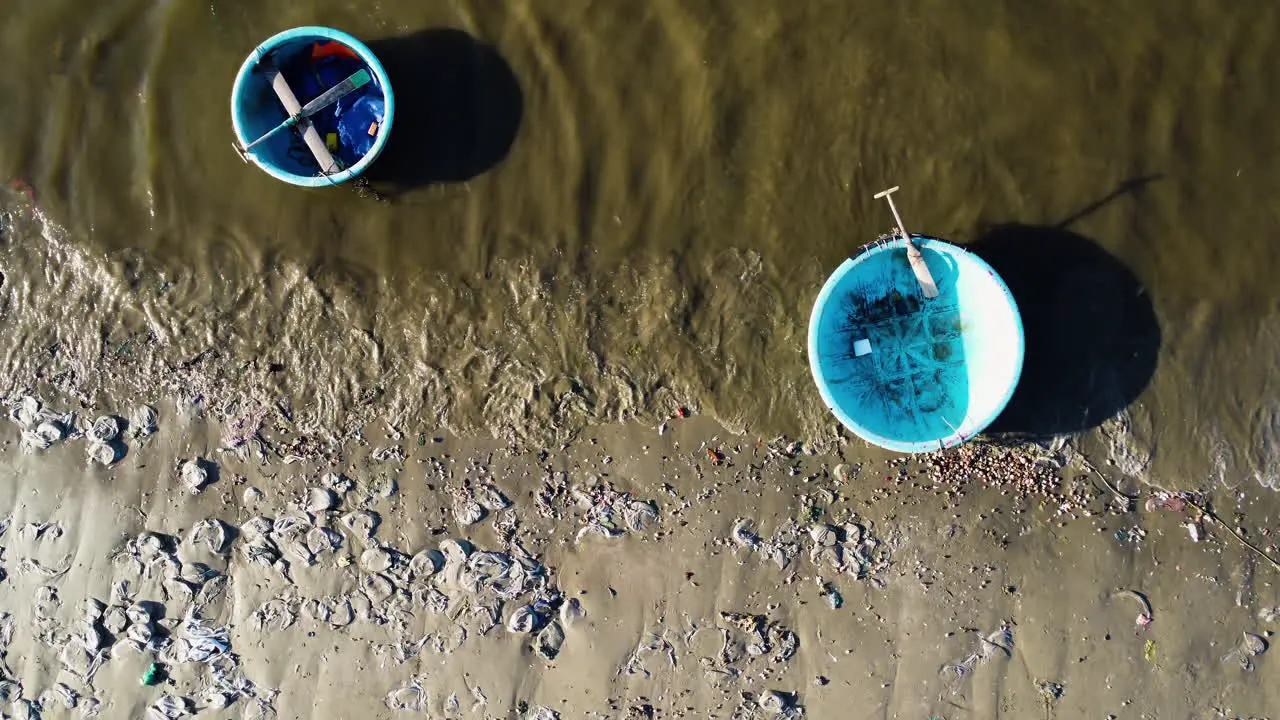 Vietnamese Coracle boats and sandy beach full of washed out plastic aerial top down view