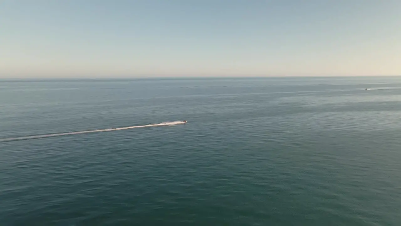 Fast aerial view following speeding jet ski across seascape ocean horizon