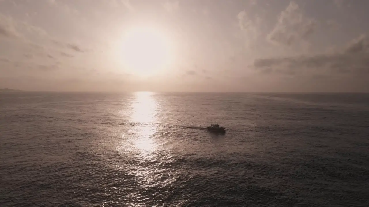 Aerial view silhouetted boat travelling across dramatic shimmering sunset seascape