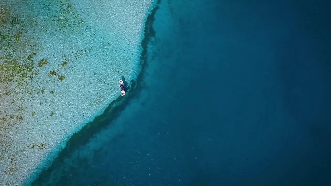 Aerial view of a small fishing boat floating in the blue Caribbean sea at Los Roques Venezuela