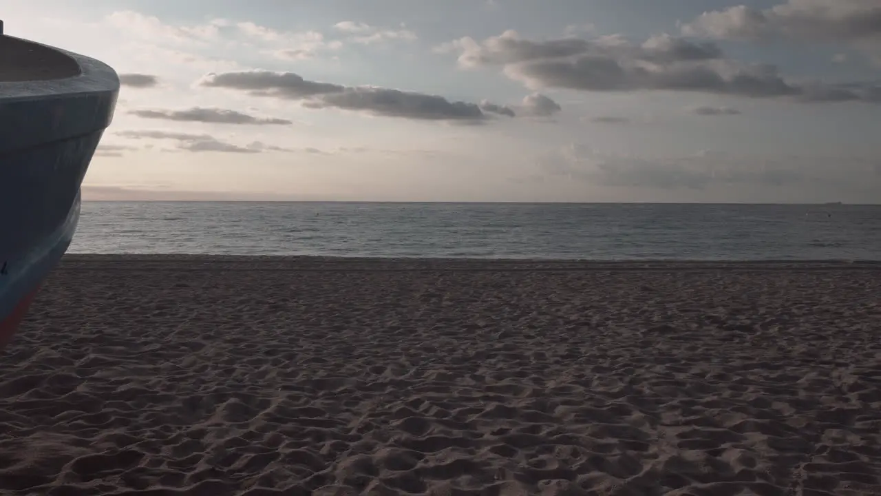 4K clip pan to the right of a classic little fisherman boat on the sand of a beach of the Mediterranean sea at sunrise showing a sunburst