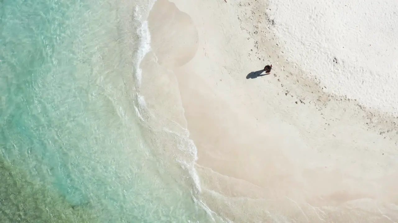 Aerial Single woman tourist wearing sarong strolls on beach during summer vacation near Puerto Plata