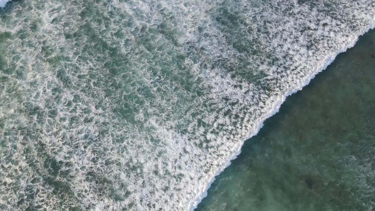 4K aerial top view of waves foam in beautiful turquoise sea texture background