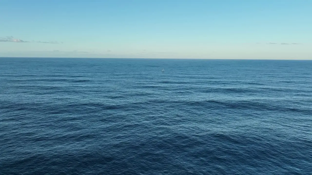 Aerial wide shot of single lone Sailing Yacht in ocean at full sail