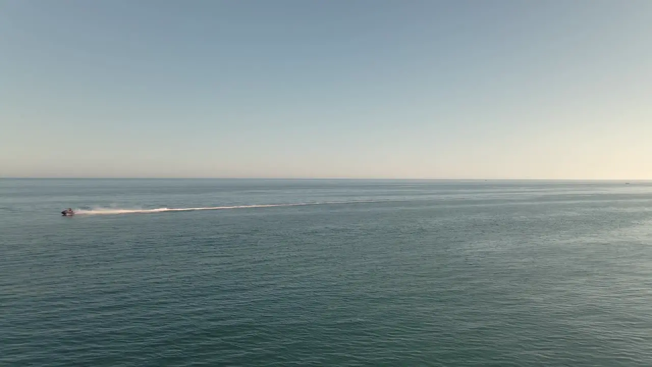 Fast aerial view speeding jet ski across seascape ocean horizon right to left