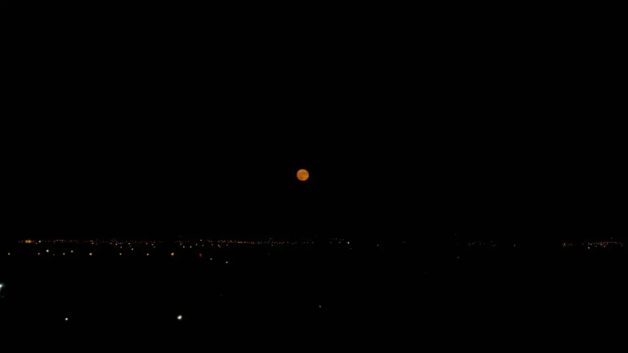 Night footage of orange full moon over cityscape near international airport of Athens 4k