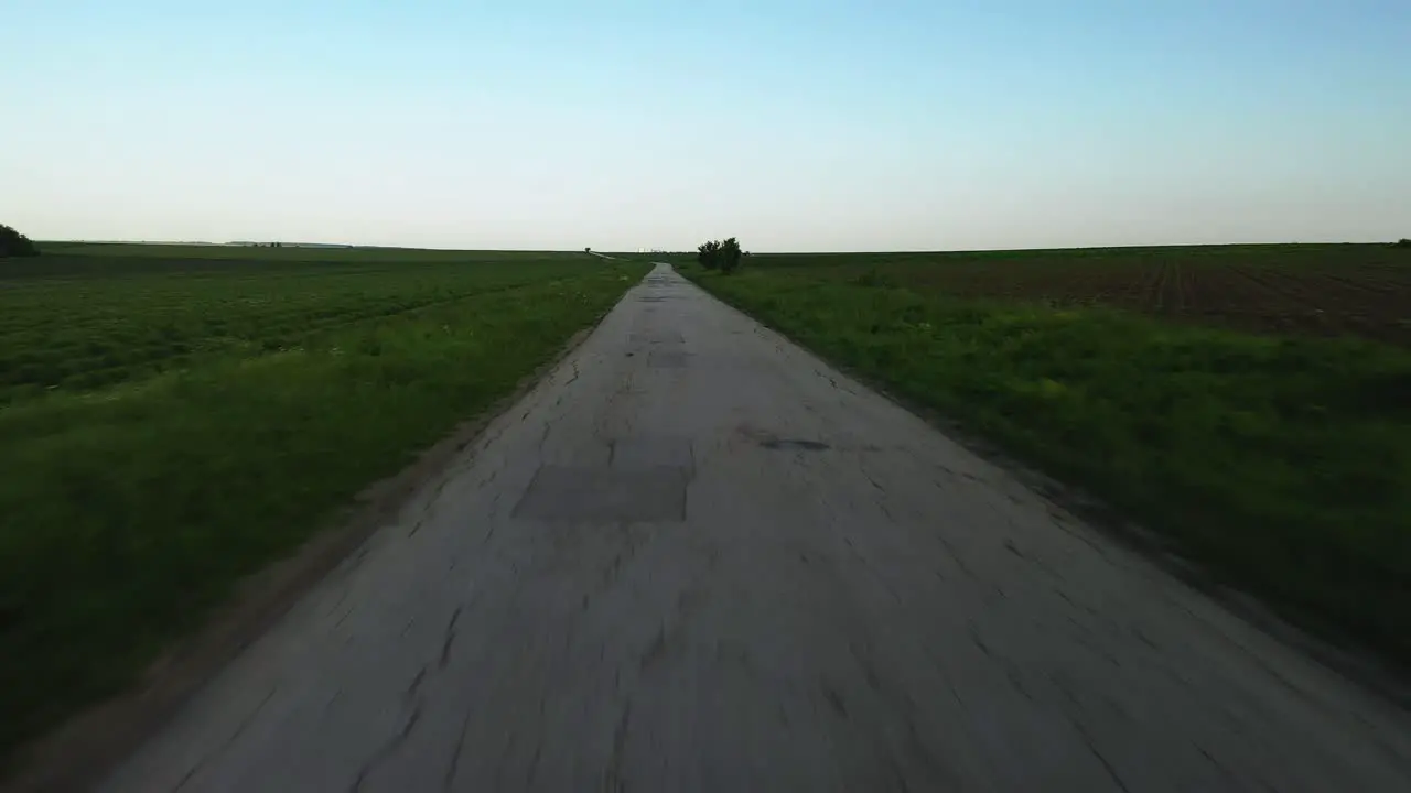 Empty Road with Potholes in the Fields With a Big Tree and Beautiful Blue Sky