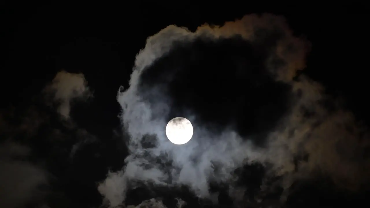 Eerie Night Sky Unveiled Full Moon Timelapse with Ominous Clouds Casting Shadows Over a Bright Moon Shrouded in Dark Dust