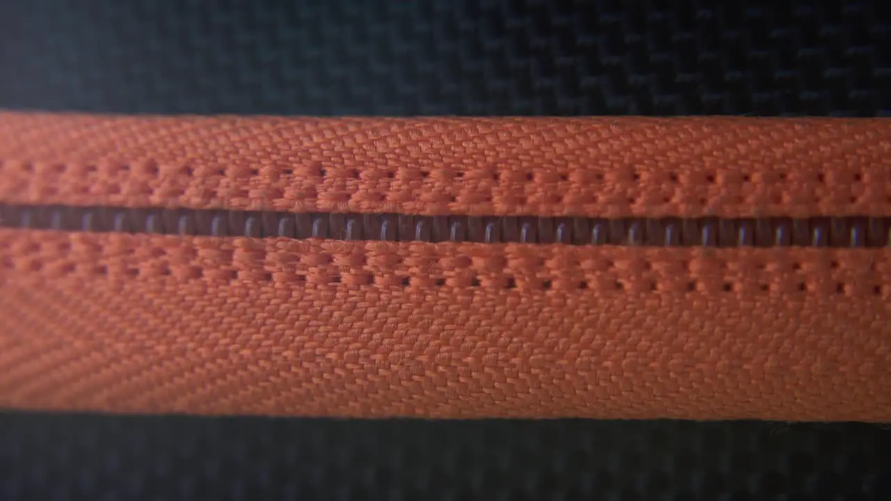 A cinematic macro close-up shot of a hard case zipper being opened orange rexture metal zip black box photography gear professional studio lighting static 4K video